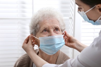 Photo of Doctor putting protective mask on senior woman at nursing home