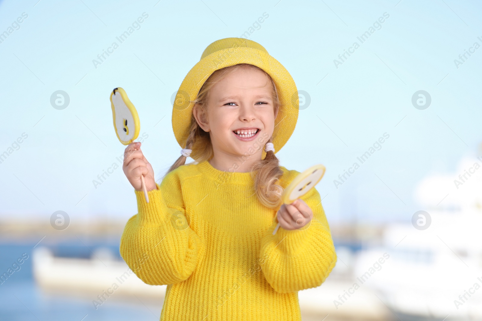 Photo of Cute little girl with tasty candies outdoors