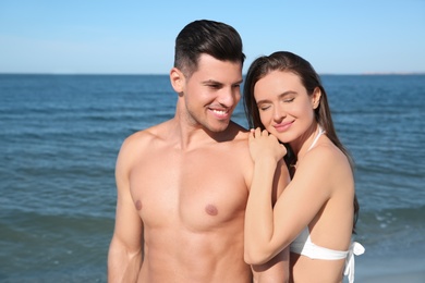 Photo of Woman in bikini and her boyfriend on beach. Happy couple