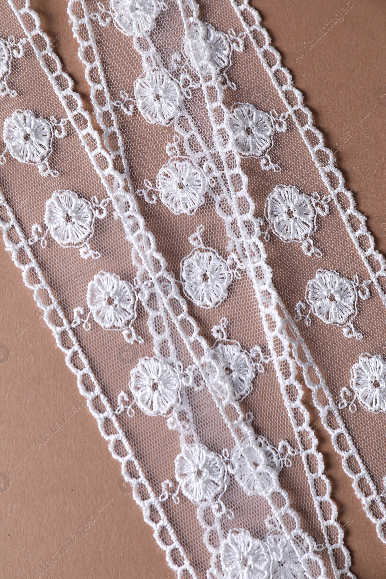 Photo of White lace on beige background, top view