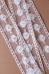 Photo of White lace on beige background, top view