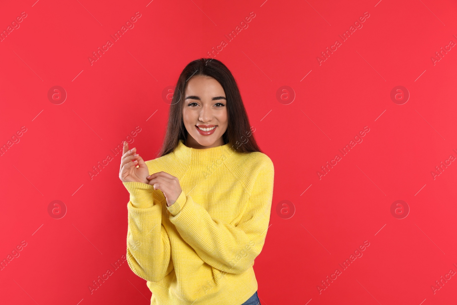 Photo of Beautiful young woman wearing yellow warm sweater on red background. Space for text