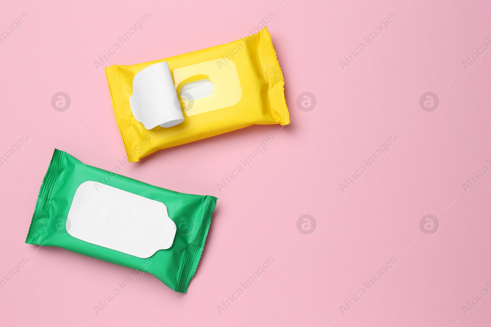 Photo of Wet wipes flow packs on pink background, flat lay. Space for text