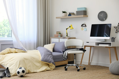 Stylish teenager's room interior with comfortable bed and workplace