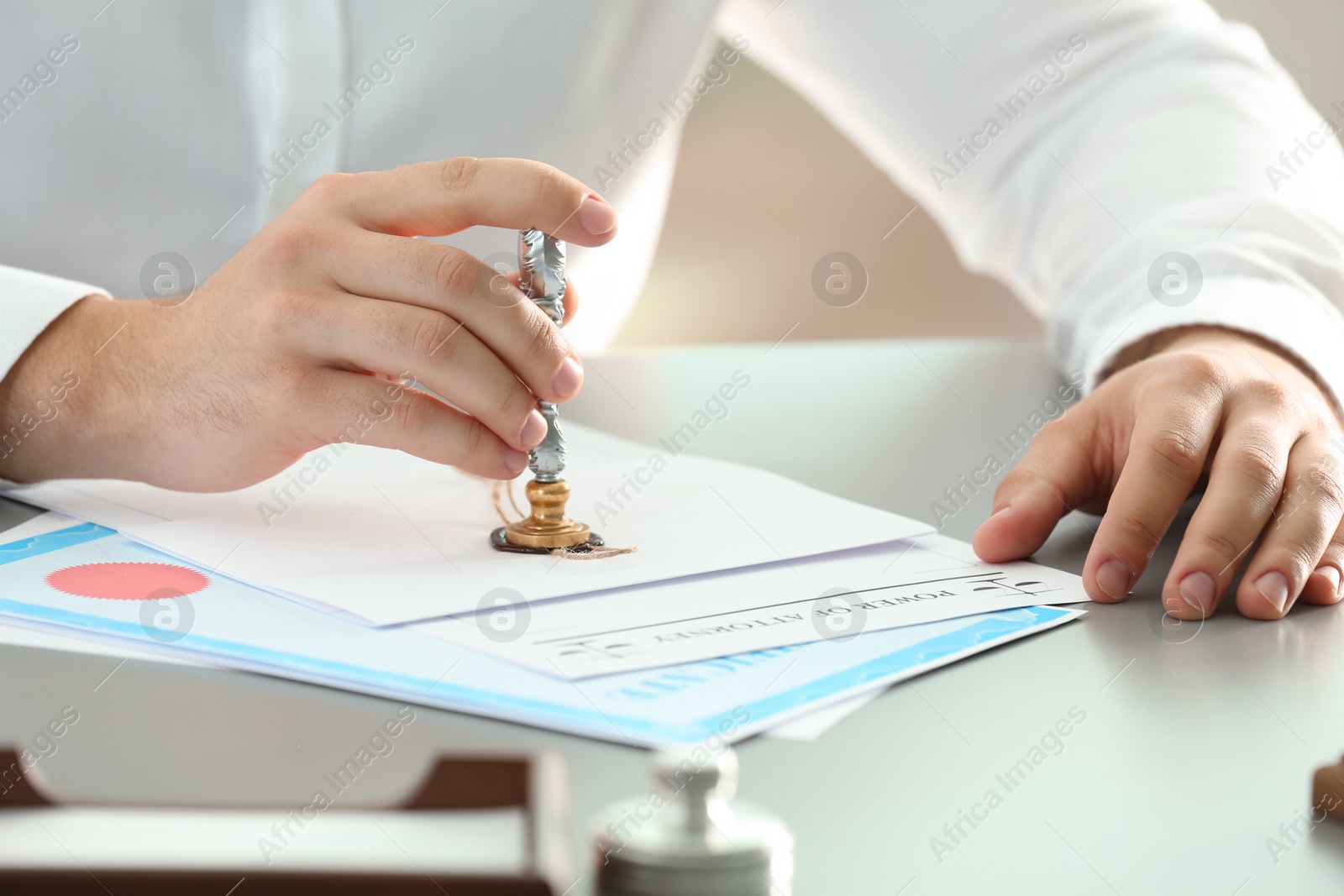 Photo of Male notary sealing document at table, closeup