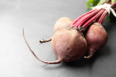 Photo of Raw ripe beets on black slate table. Space for text