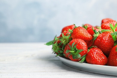 Photo of Plate with ripe red strawberries and mint on wooden table