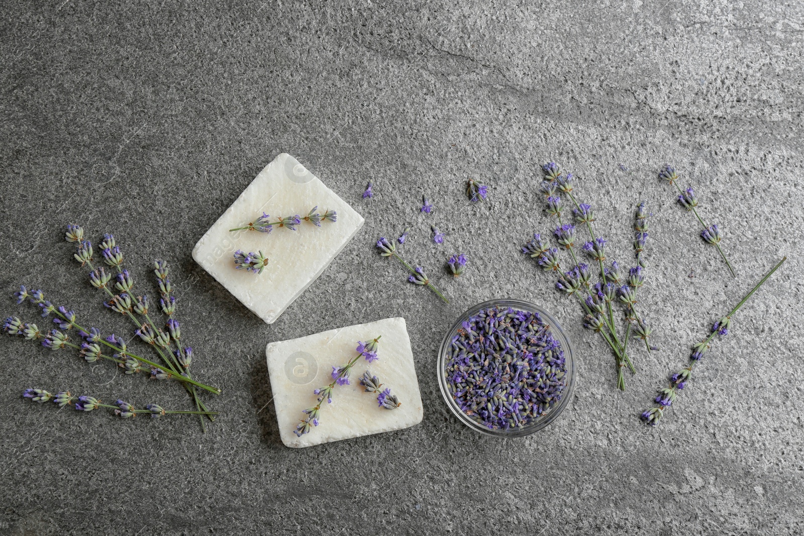 Photo of Flat lay composition with hand made soap bars and lavender flowers on grey stone table