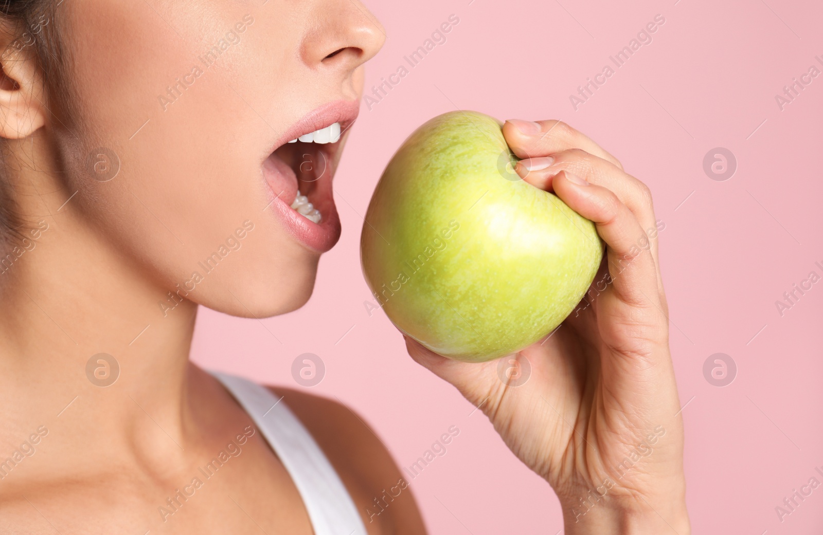 Photo of Young woman with healthy teeth and apple on color background, closeup