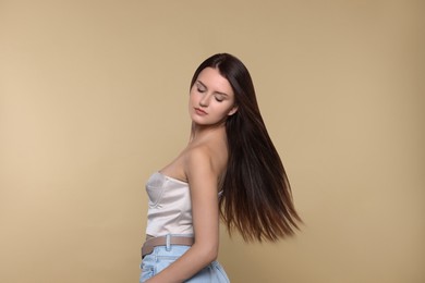 Photo of Portrait of beautiful young woman with healthy strong hair on beige background