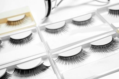 Photo of Set with different false eyelashes in packs as background, closeup