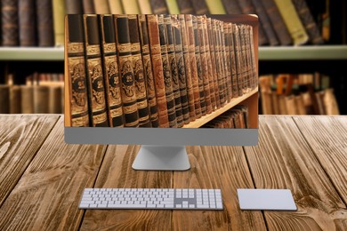 Online library. Modern computer on wooden table and shelves with books indoors