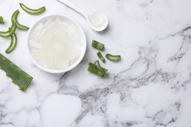 Aloe vera gel and slices of plant on white marble table, flat lay. Space for text