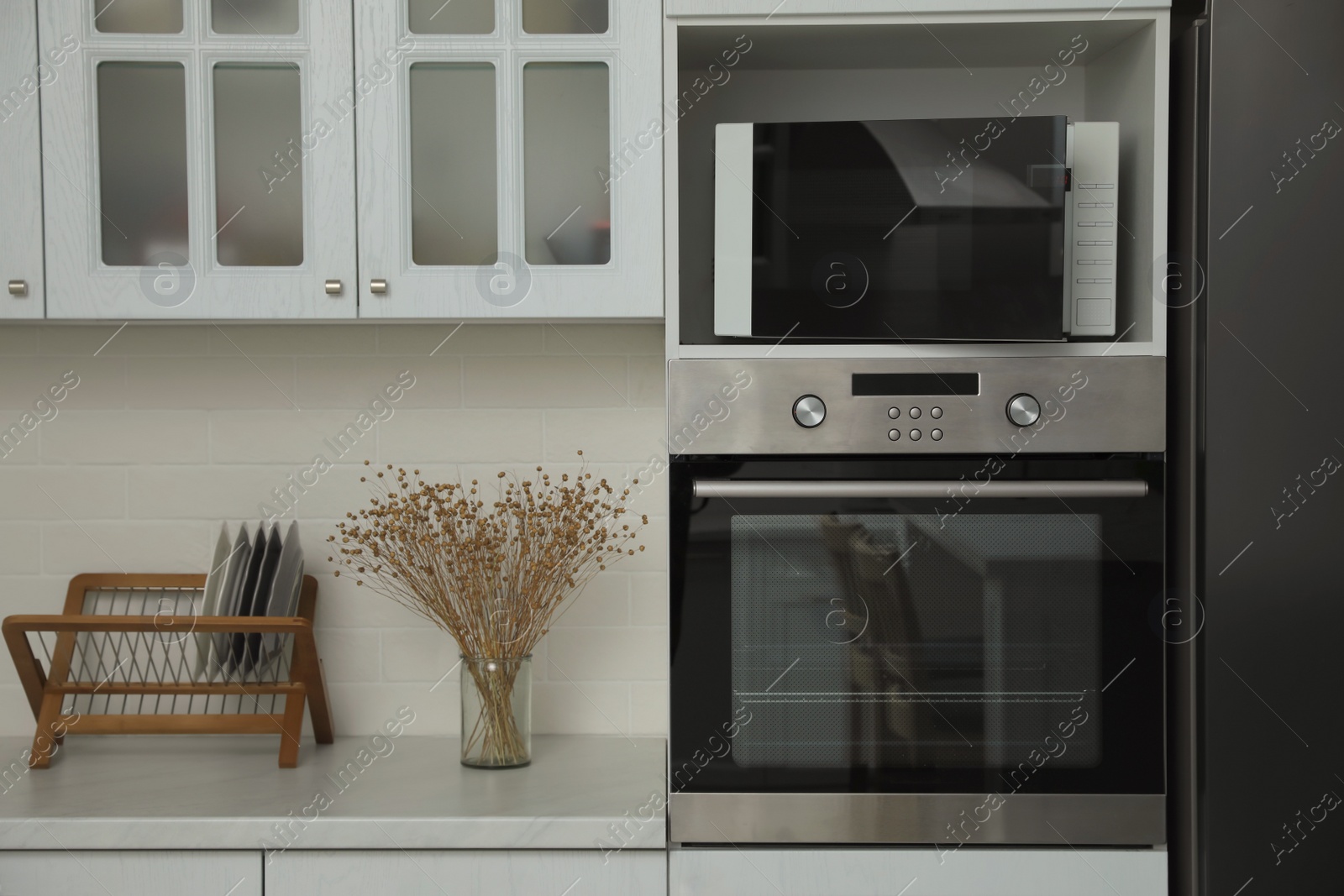 Photo of Modern microwave oven on shelf in kitchen