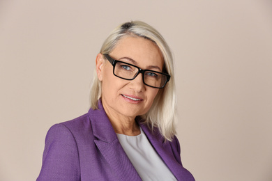 Photo of Portrait of beautiful mature woman with glasses on beige background