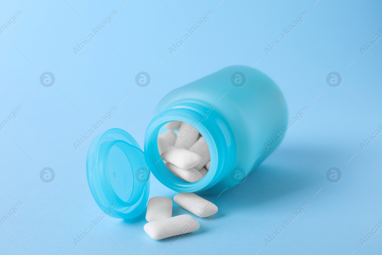 Photo of Jar with tasty chewing gums on light blue background