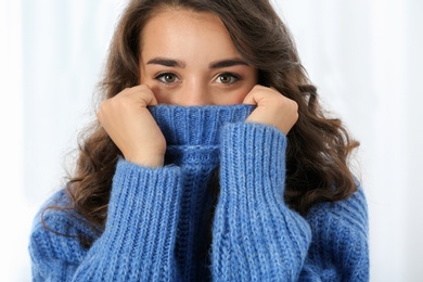 Portrait of young beautiful woman in warm sweater on light background