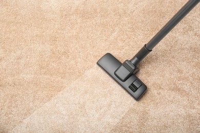 Image of Vacuuming dirty beige carpet. Clean area after using device, top view