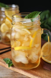 Photo of Delicious iced tea in mason jar on wooden table