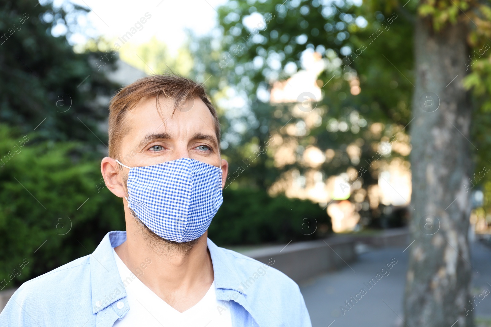 Photo of Man wearing handmade cloth mask outdoors, space for text. Personal protective equipment during COVID-19 pandemic