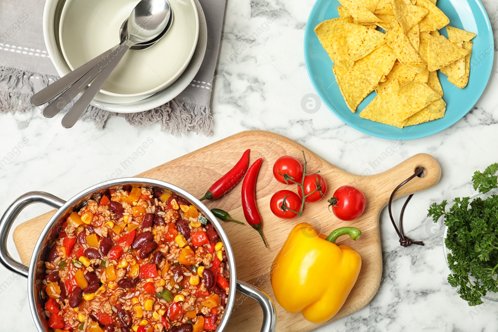 Photo of Delicious chili con carne served on marble table, flat lay