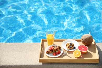Tray with delicious breakfast near swimming pool. Space for text