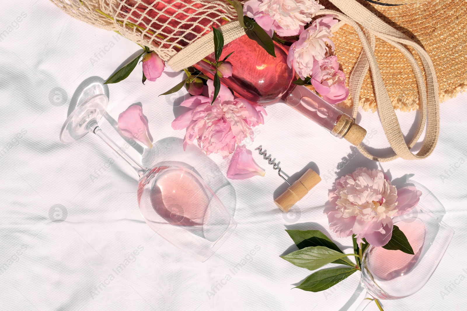 Photo of Flat lay composition with beautiful peonies and rose wine on white fabric