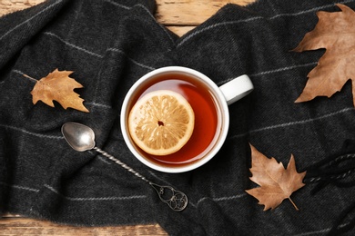 Photo of Flat lay composition with hot cozy drink, scarf and autumn leaves on table