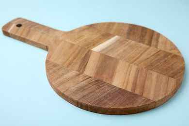 Photo of One wooden board on light blue background, closeup