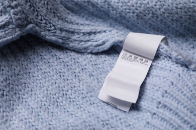 Photo of Clothing label on light blue garment, closeup. Space for text
