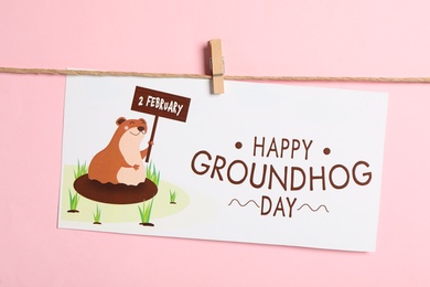 Photo of Happy Groundhog Day greeting card hanging on pink background