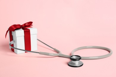 Photo of Stethoscope and gift box on pink background. Happy Doctor's Day