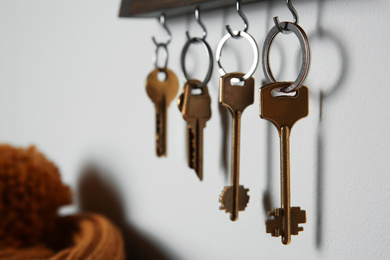 Photo of Holder with different keys on light grey wall indoors