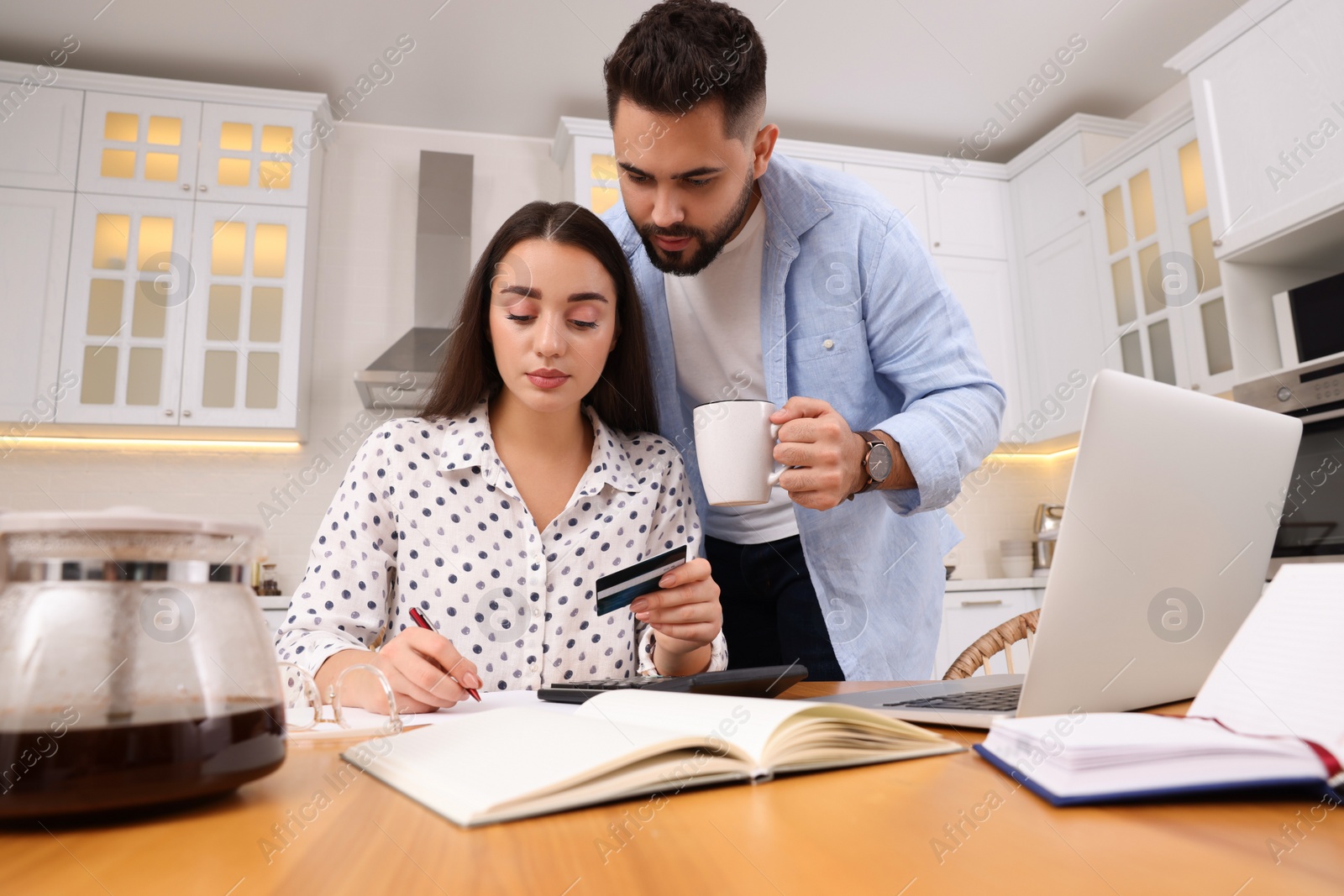 Photo of Young couple discussing family budget in kitchen