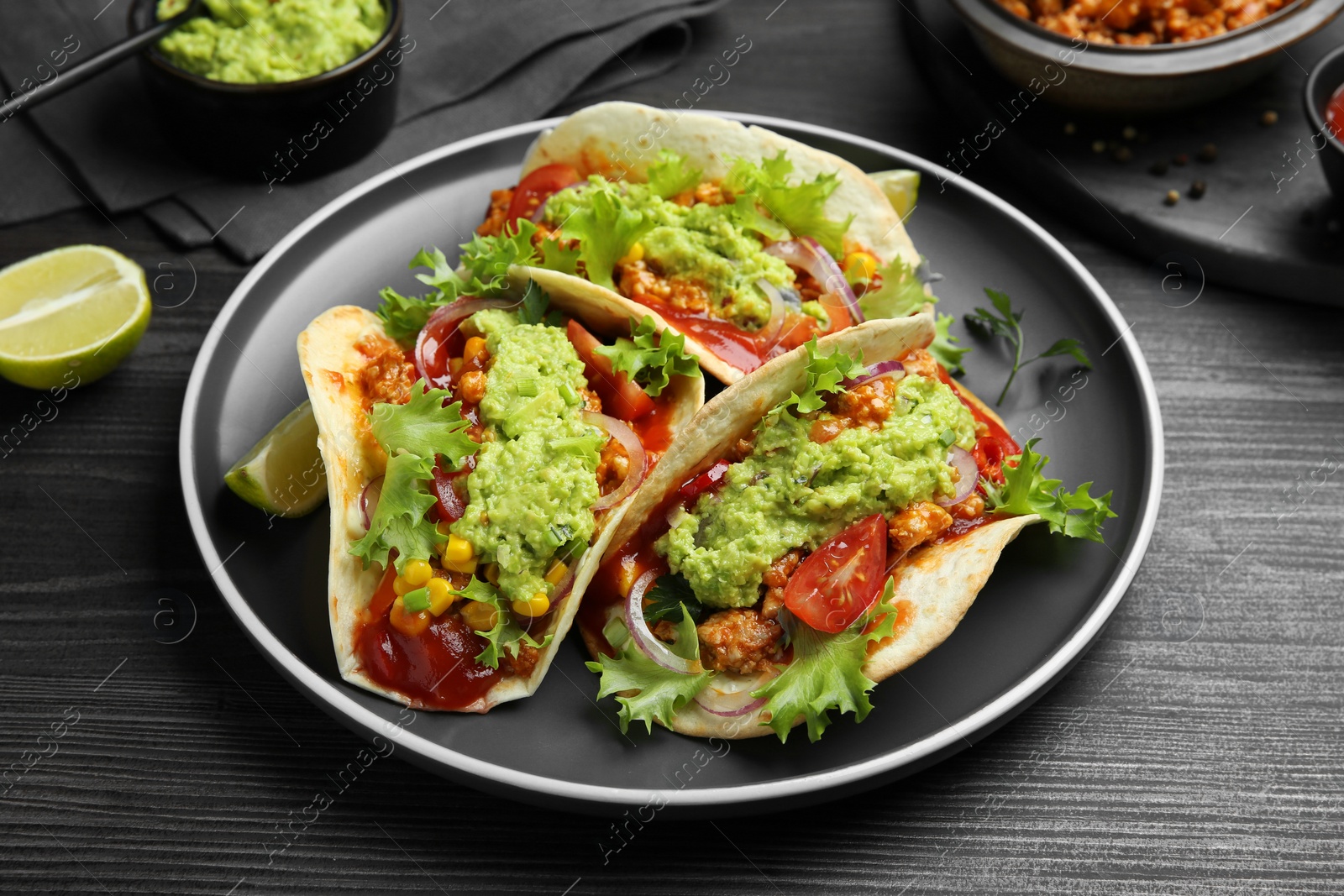 Photo of Delicious tacos with guacamole, meat and vegetables on wooden table