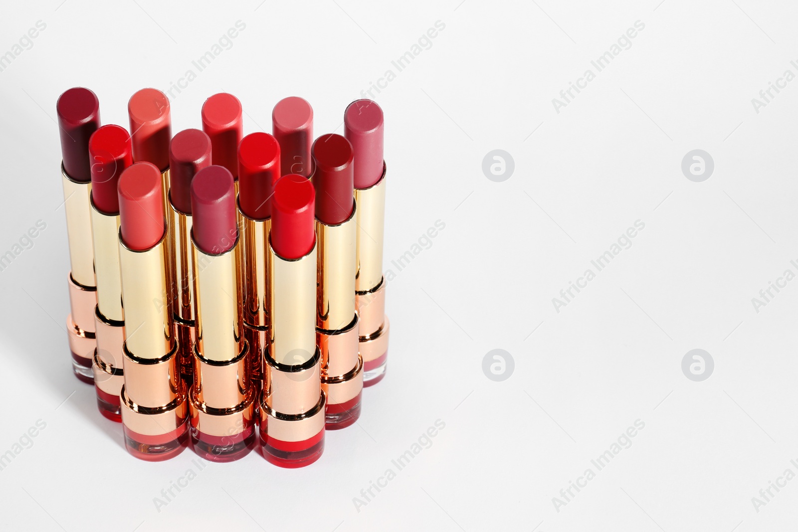 Photo of Set of bright lipsticks in gold tubes on white background