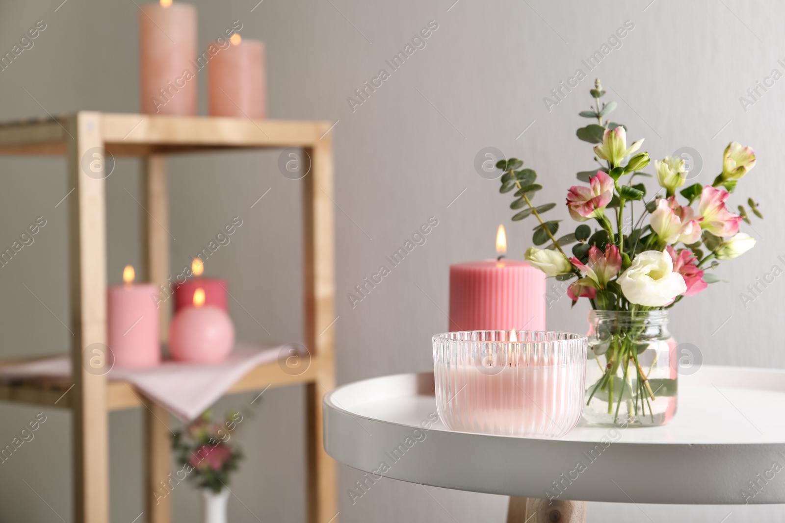 Photo of Stylish tender composition with burning candles and flowers on white table indoors, space for text. Cozy interior element