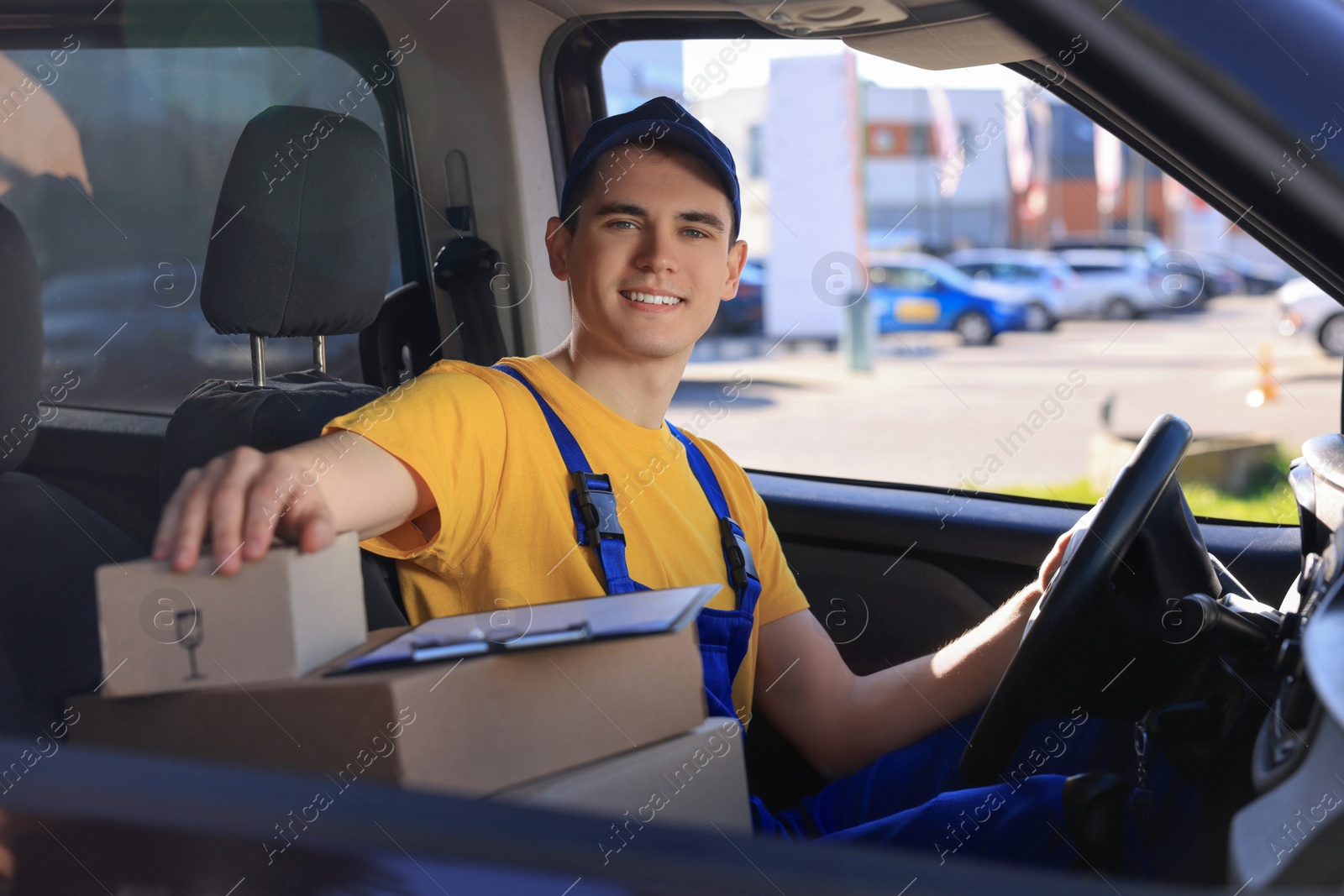 Photo of Courier with clipboard and parcels in car. Delivery service