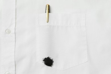 Photo of White shirt with stain of black ink and pen in pocket, top view
