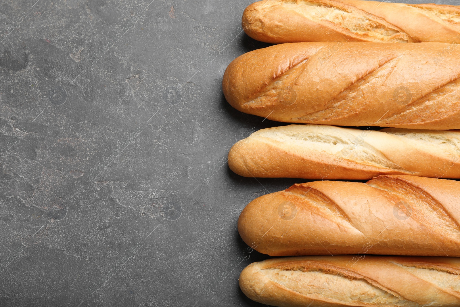 Photo of Different tasty baguettes on grey table, flat lay. Space for text