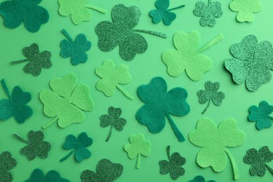 Photo of St. Patrick's day. Decorative clover leaves on green background, flat lay