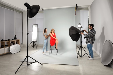 Professional photographer and assistant working with model in modern studio