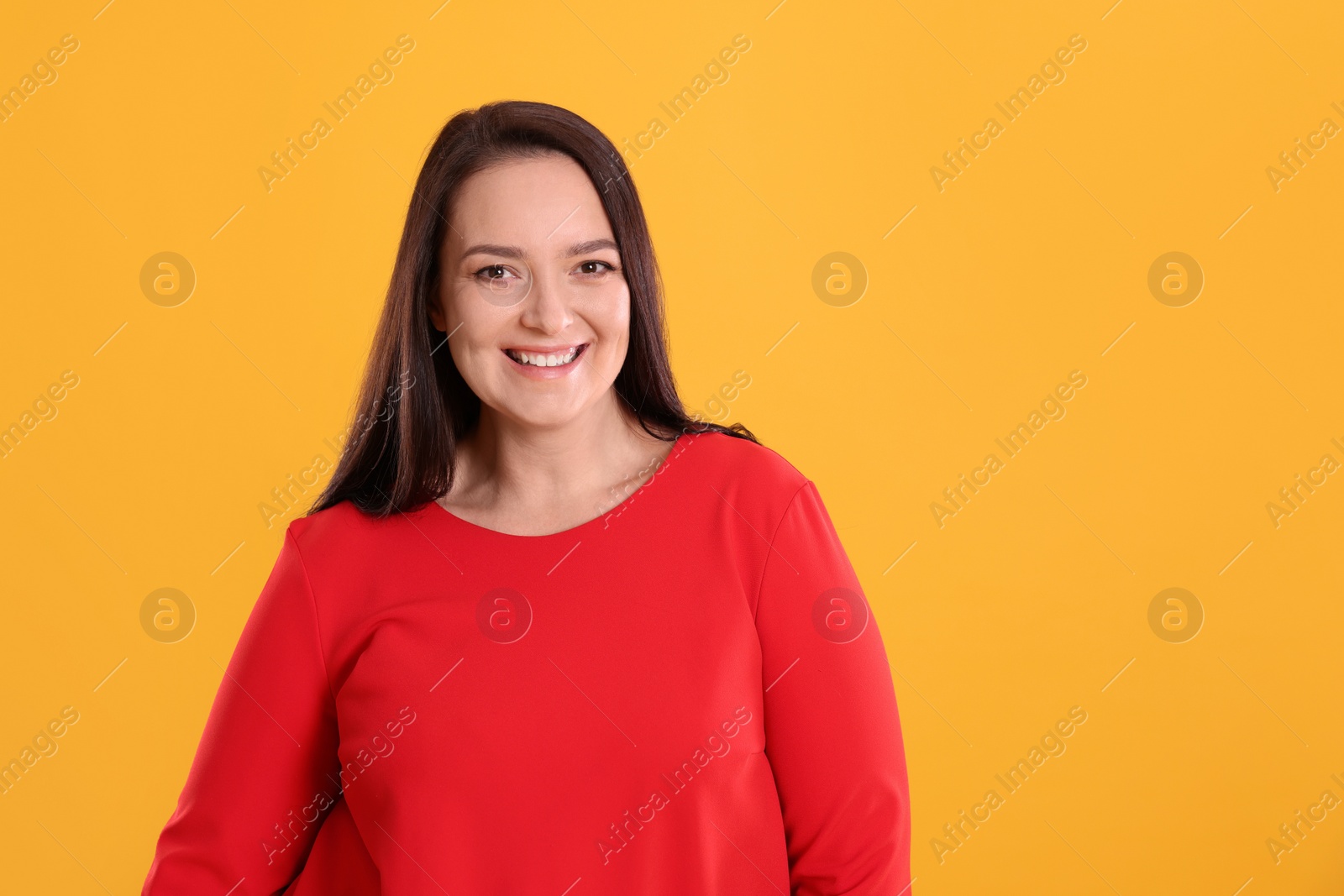 Photo of Beautiful overweight woman in red dress on yellow background. Space for text