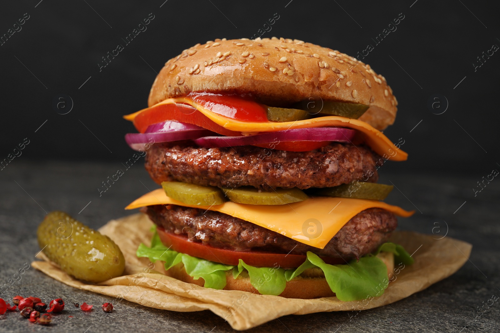 Photo of Delicious burger with meat cutlets, cheese, pickled cucumbers and lettuce on grey table, closeup