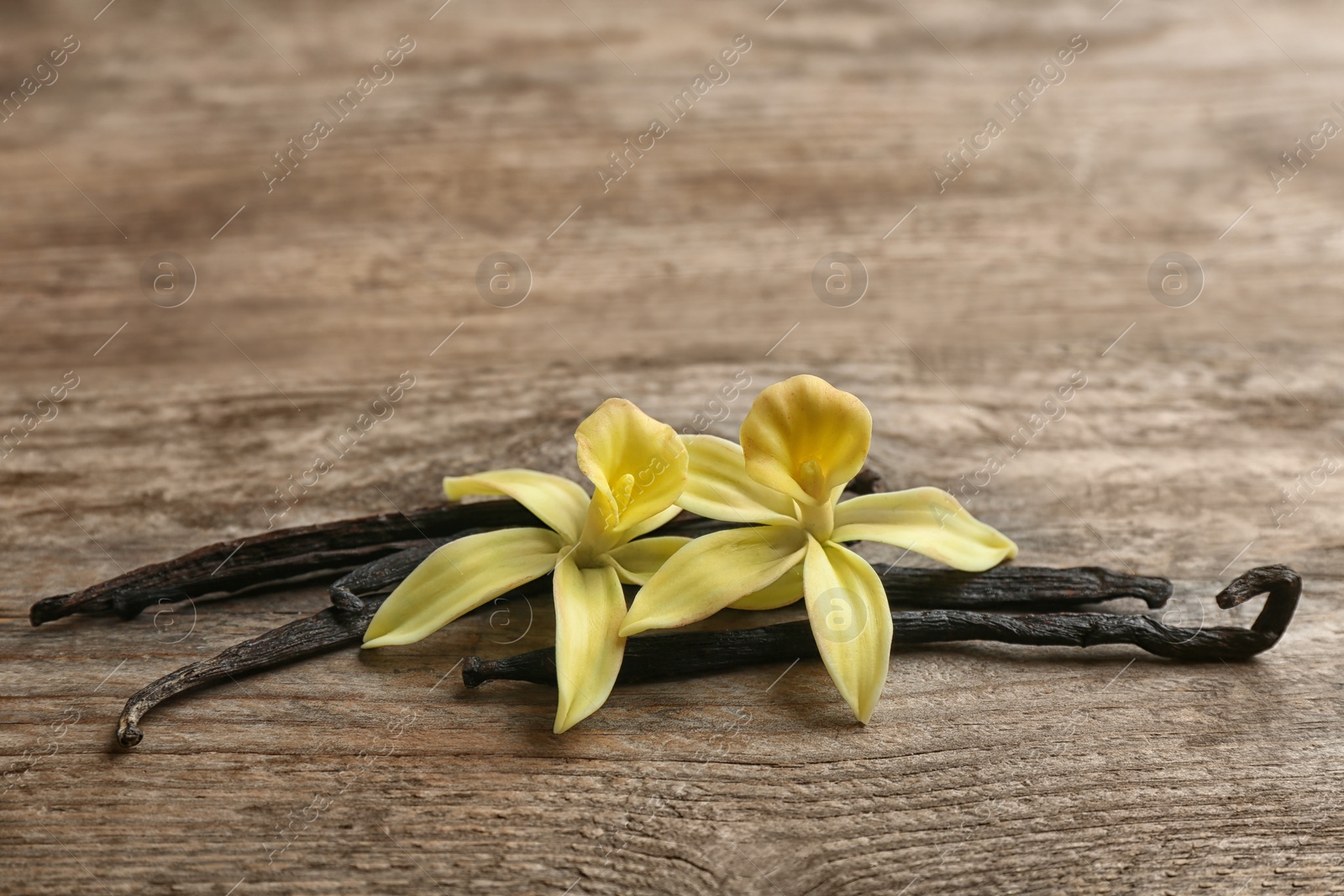 Photo of Vanilla sticks and flowers on wooden background. Space for text