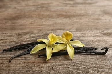 Vanilla sticks and flowers on wooden background. Space for text