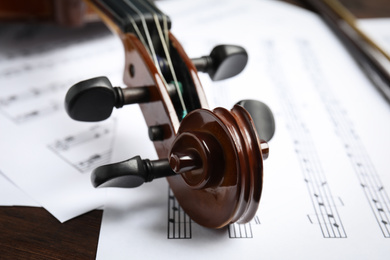 Photo of Beautiful violin and note sheets on table, closeup