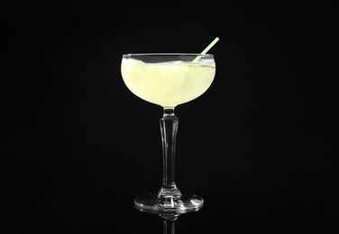 Glass of delicious cucumber martini with ice on dark background