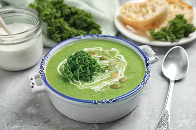 Photo of Tasty kale soup with pumpkin seeds on light grey marble table, closeup