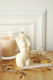 Photo of Beautiful female body shape candle on wooden table. Stylish decor